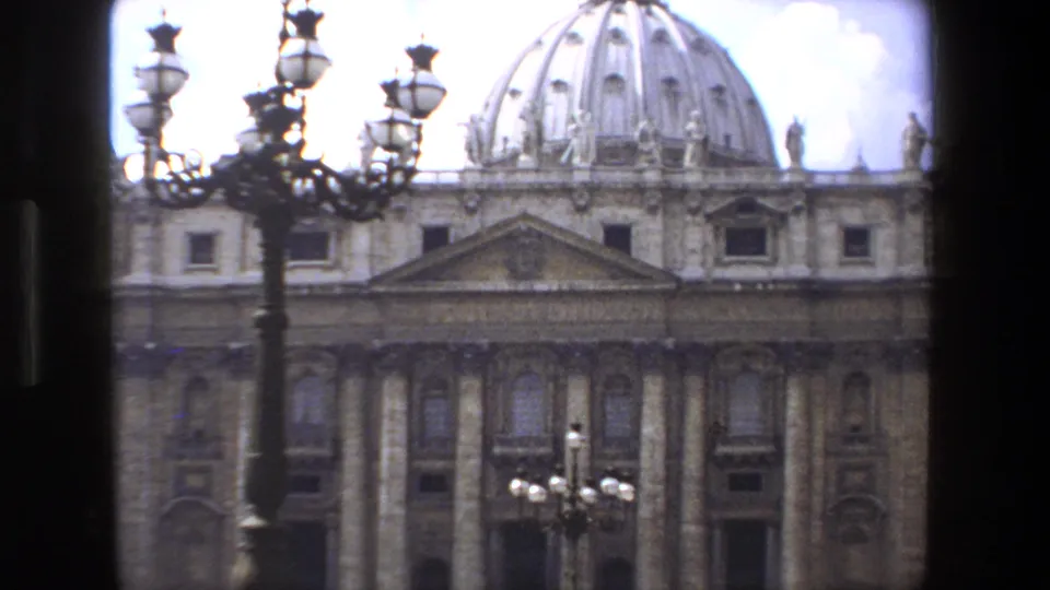 1973 8mm Rome-area Vatican footage showing the facade and dome of St. Peter's Basilica with decorative street lamps in the foreground.