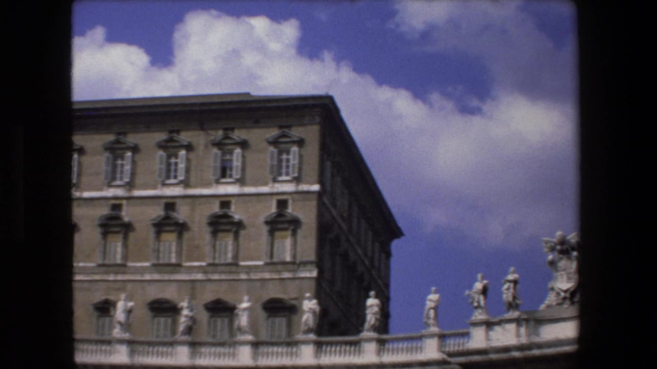 1973 Vatican City exterior view showing the Apostolic Palace facade behind the curved colonnade and rooftop statues under a bright blue sky.