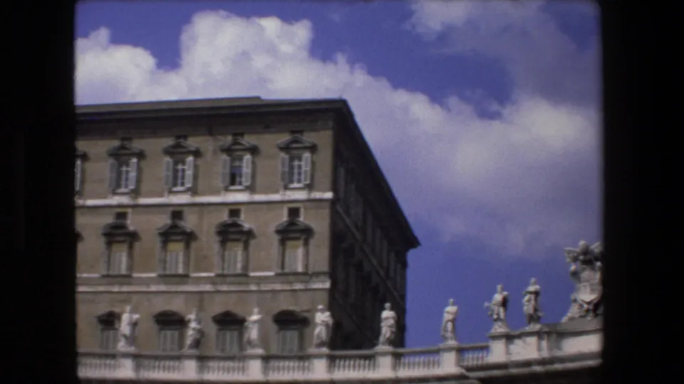 1973 Vatican City exterior view showing the Apostolic Palace facade behind the curved colonnade and rooftop statues under a bright blue sky.