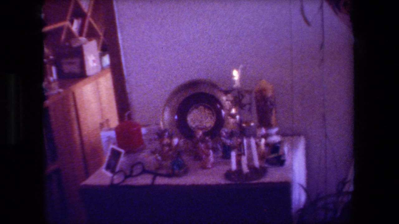 Dim living room table with decorative objects, candles, a plate, and a red container.
