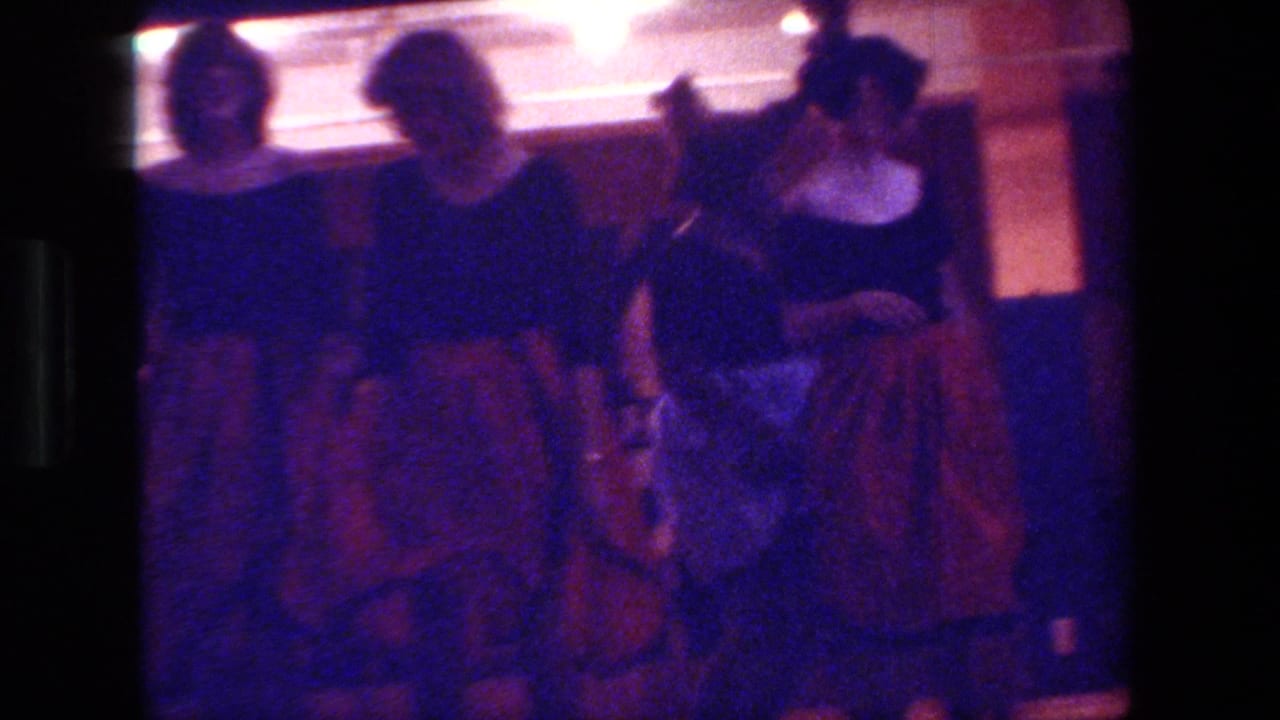 Three adult dancers stand close together in dark tops and full skirts.