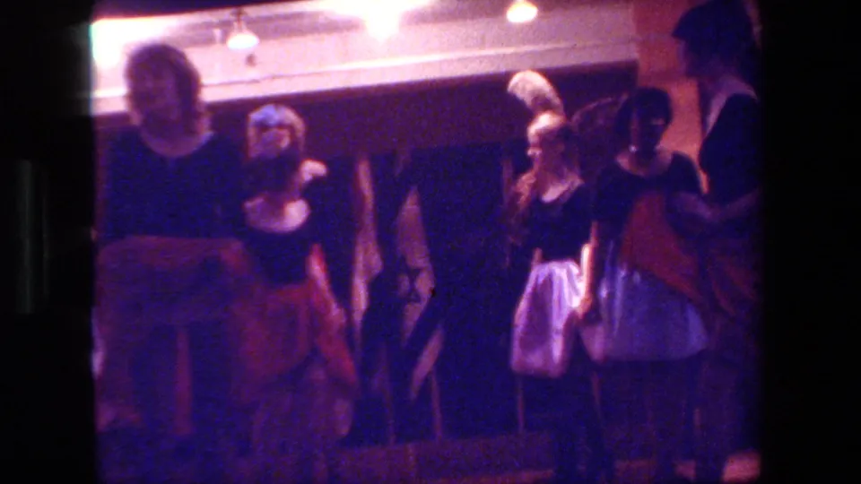 The final frame shows adult female dancers in black tops and contrasting skirts moving across a dim 1981 Hollywood club or theater interior, filmed from an audience-side position.