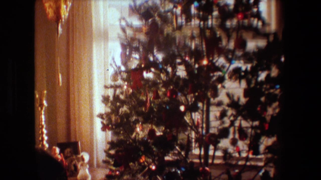 A decorated Christmas tree with colored ornaments and small lights stands near a curtained window in a dim Lansing, Michigan home interior from the 1981 8mm footage.
