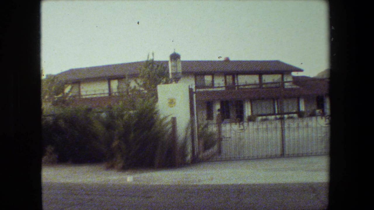 Gated two-story house with a lantern-topped pillar and front vegetation.