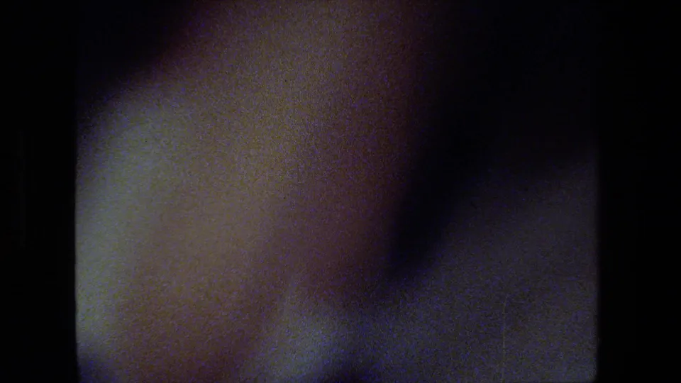 Final 8mm frame with a dark, out-of-focus obstruction or exposure change obscuring the Malibu house scene, leaving only vague color and shadow shapes visible.