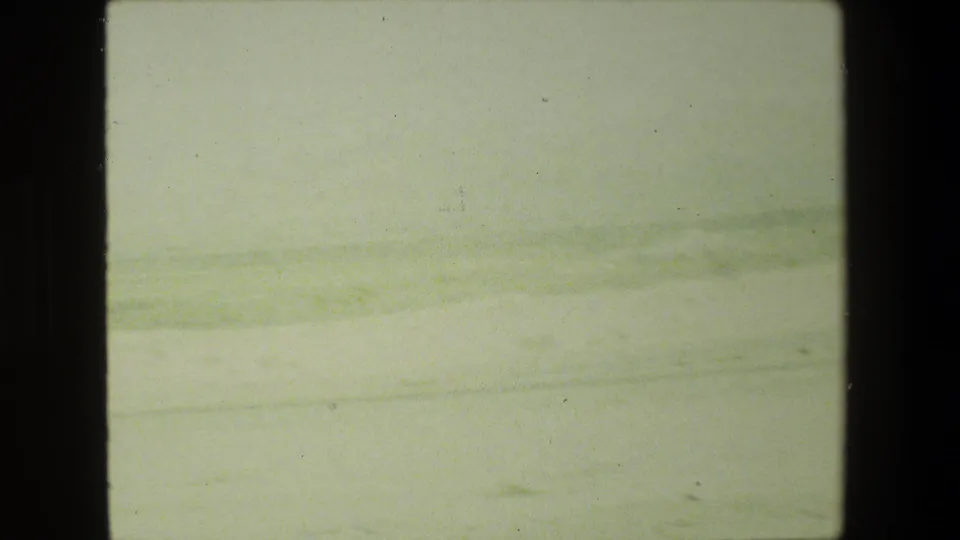 1981 8mm home-movie frame from the Malibu, California metadata showing a hazy roadside landscape through dark interior window edges.