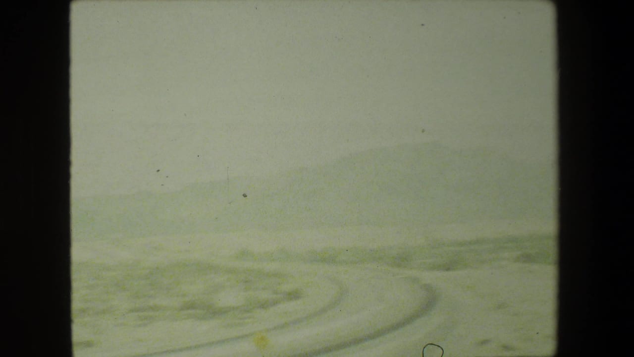 Distant hills and a sweeping road curve viewed from a moving vehicle.
