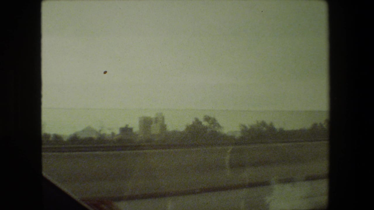 Distant buildings and trees seen through a divided car window.