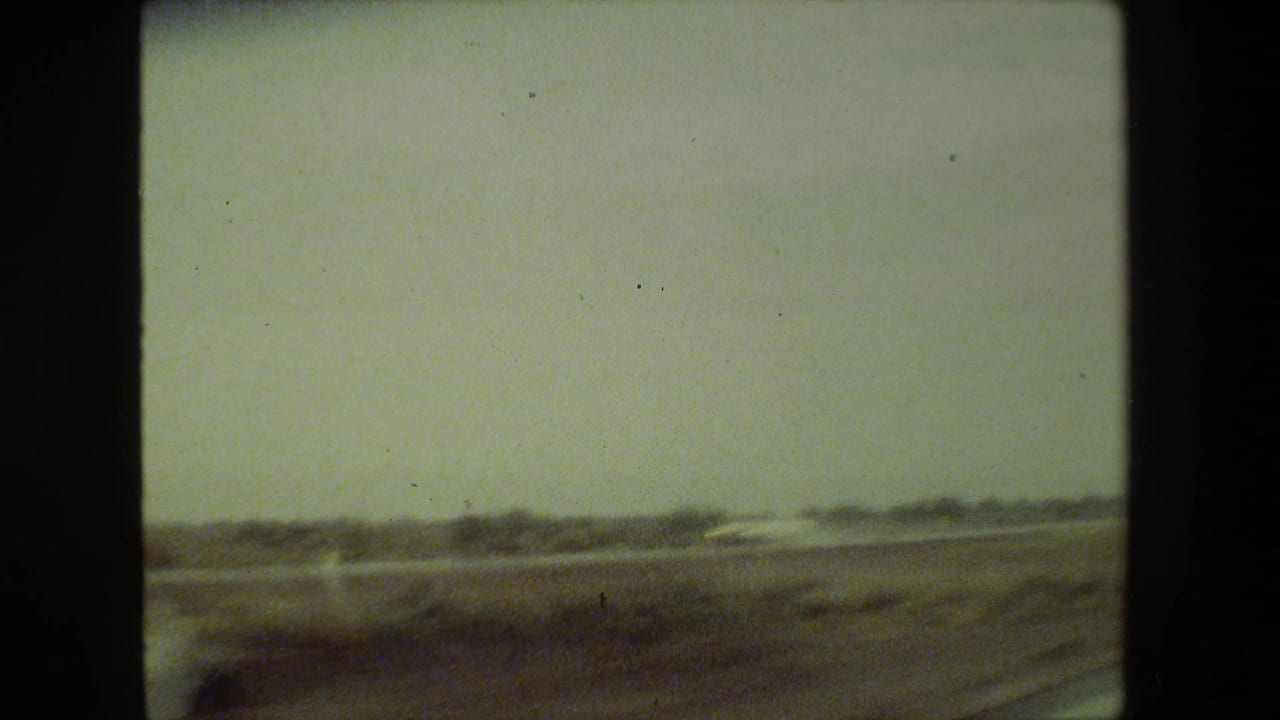 1981 Malibu-area 8mm home-movie view of hazy open roadside landscape with distant low terrain and motion blur from a moving vehicle.