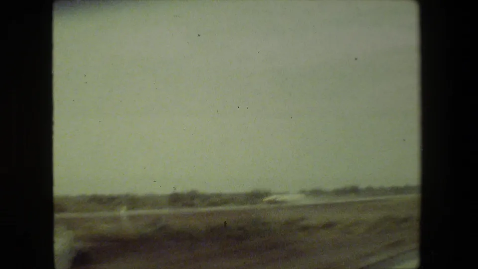 1981 Malibu-area 8mm home-movie view of hazy open roadside landscape with distant low terrain and motion blur from a moving vehicle.