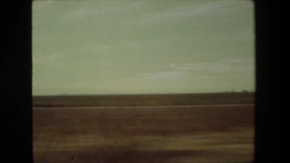 Flat arid Malibu-area landscape under a pale hazy sky, recorded on 8mm film from a moving vehicle in 1981.