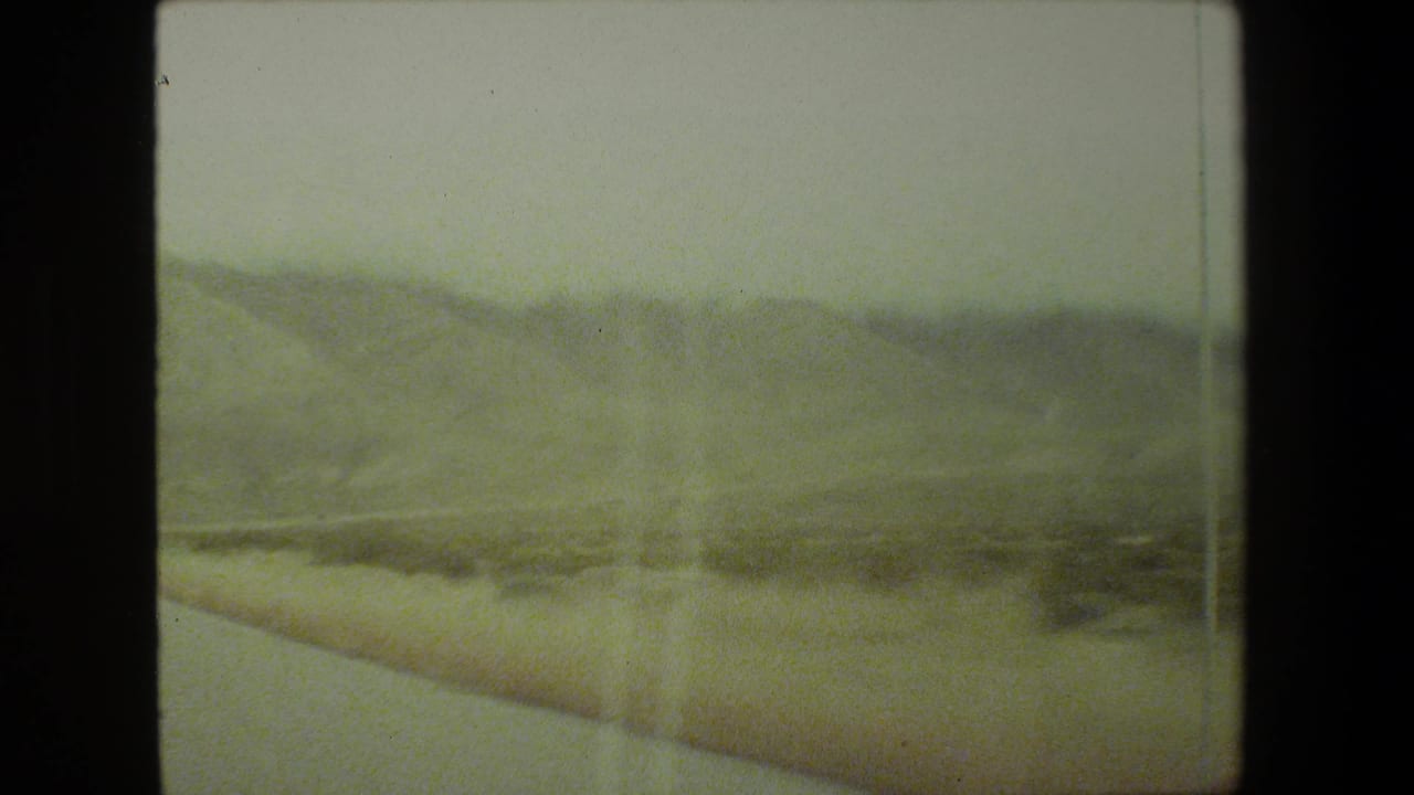 Roadside brush and distant hills seen through a blurred passenger-window view.
