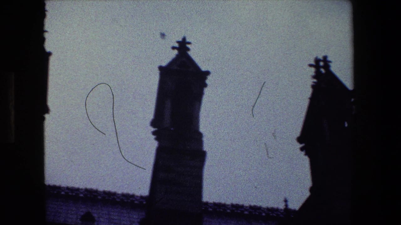 1981 Paris 8mm frame showing dark ornate spires and a roofline silhouetted against a pale sky, with visible film grain and edge shadowing.