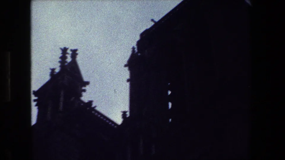 1981 Paris 8mm frame showing a low-angle view of silhouetted spires, steep roofing, and architectural edges with heavy underexposure.