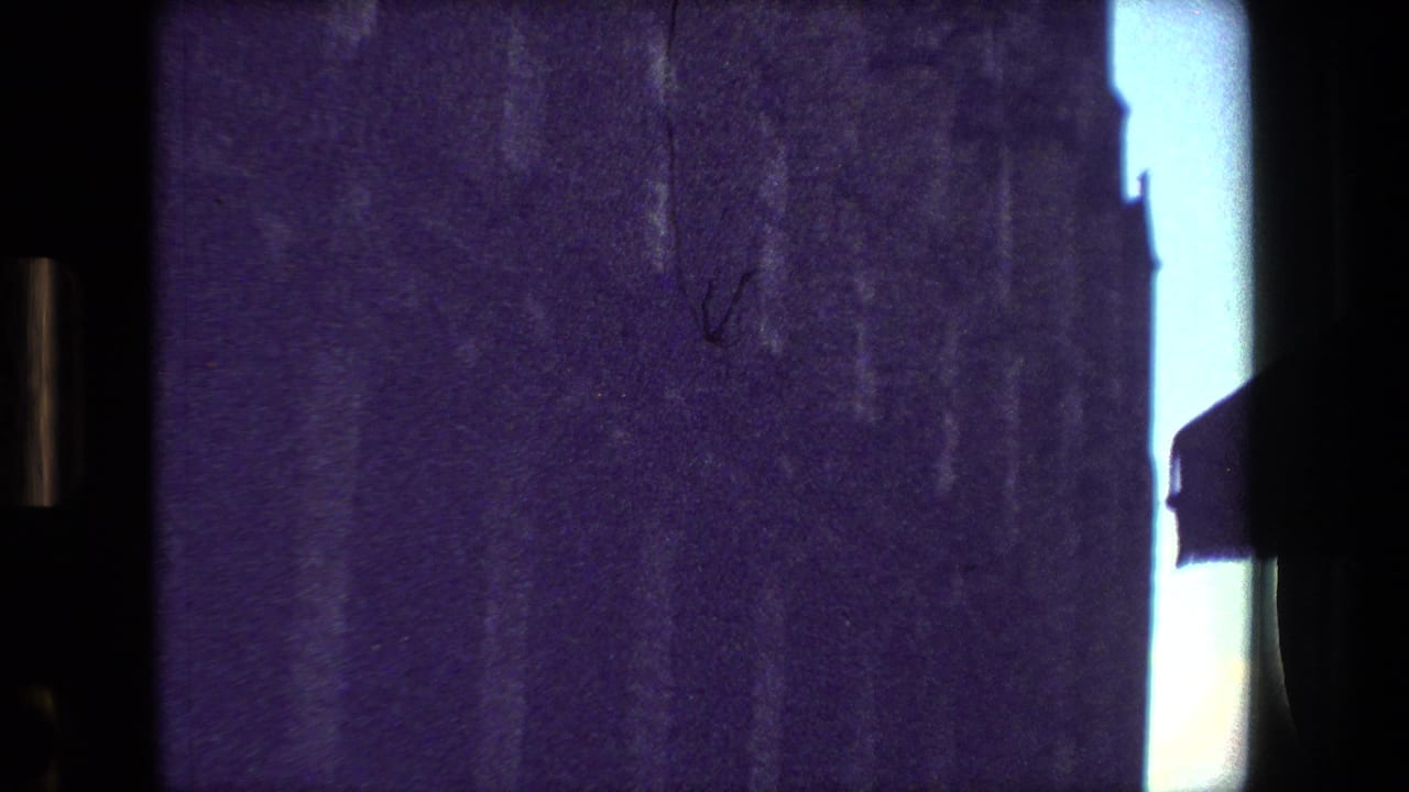 Purple-tinted 8mm frame from the supplied 1981 Paris clip, looking from a dark interior toward bright window gaps and faint exterior shapes.