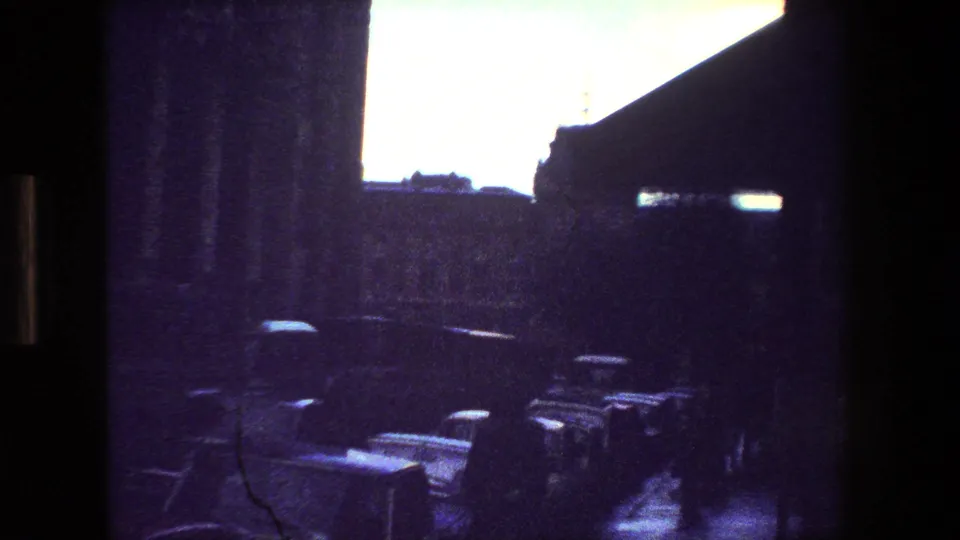 Purple-tinted 8mm frame from the 1981 Paris metadata, showing a dark interior foreground, bright exterior opening, and a row of indistinct cars or street forms.