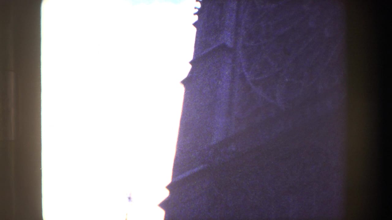 Paris 1981 8mm frame with silhouetted Gothic architectural edges partly obscured by a bright washed-out sky and dark film-gate borders.