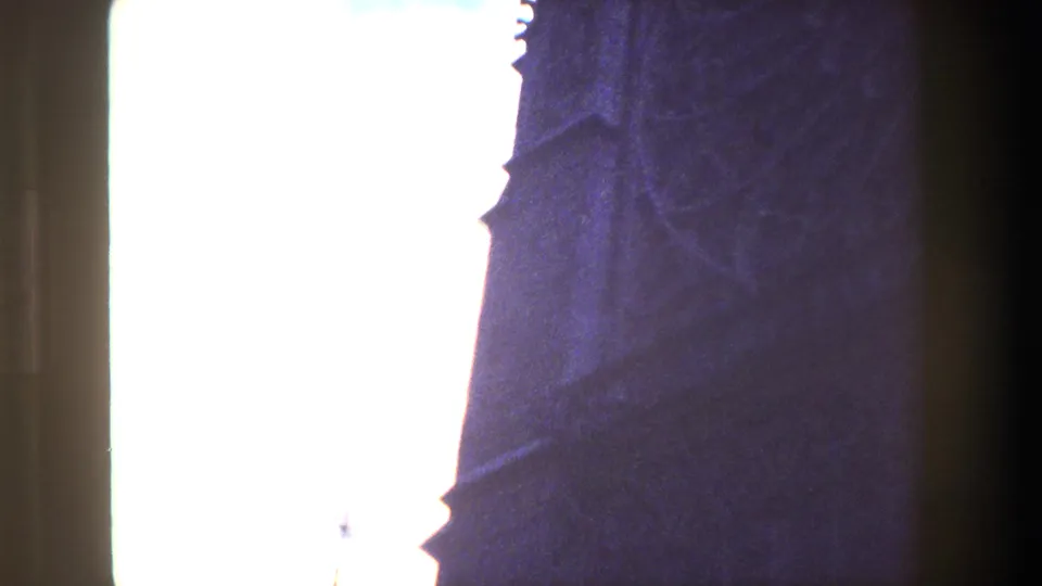 Paris 1981 8mm frame with silhouetted Gothic architectural edges partly obscured by a bright washed-out sky and dark film-gate borders.