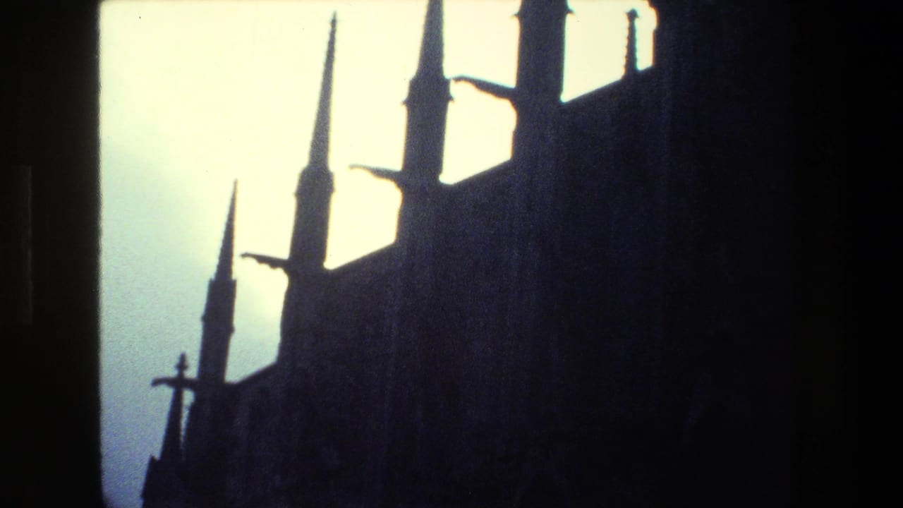 Low-angle 1981 Paris home-movie frame showing dark Gothic spires and cross forms silhouetted against a pale sky.