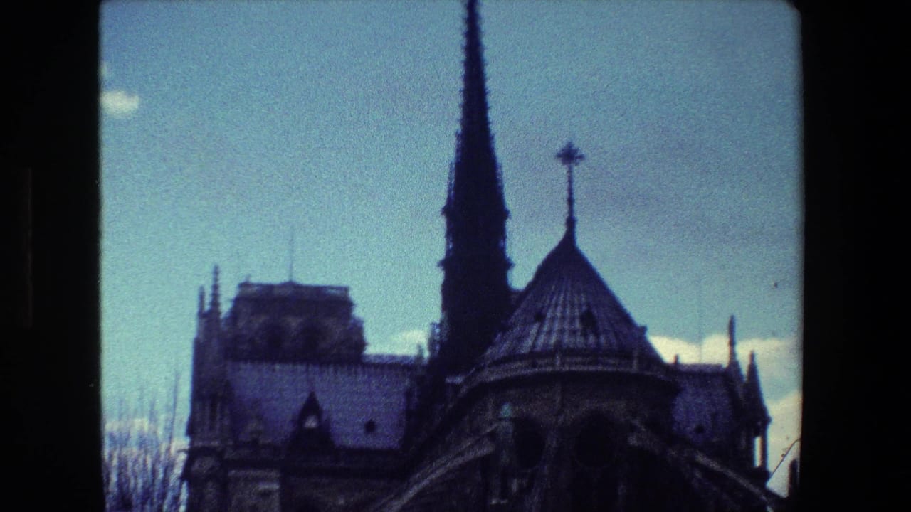 1981 Paris home-movie frame showing Notre-Dame Cathedral's roofline, spire, and upper architectural details in soft 8mm color.