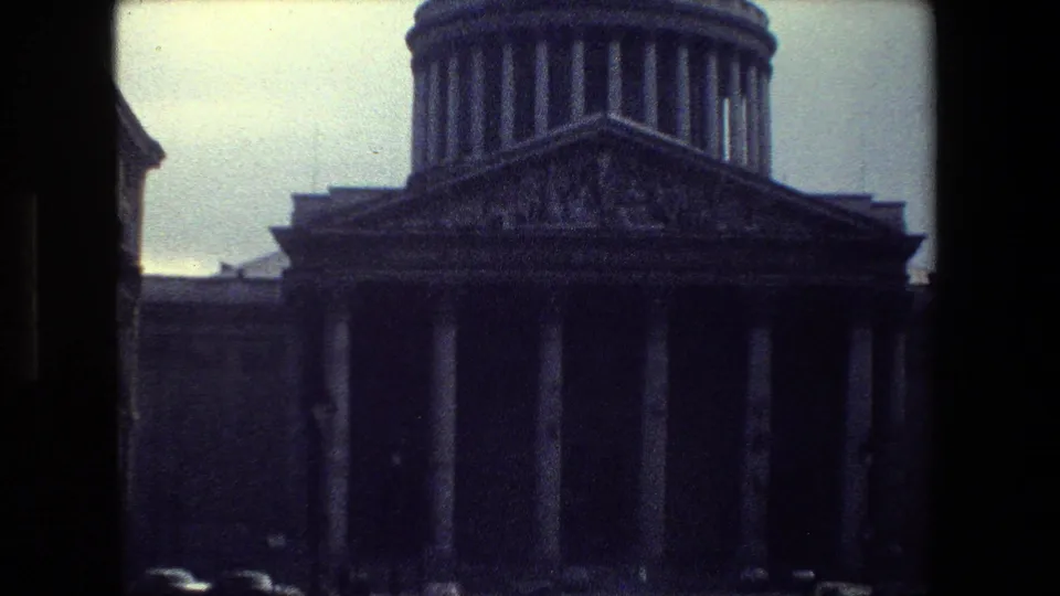 A 1981 Paris home-movie frame shows a large domed neoclassical building with tall columns, seen through dark film-frame edges from across the street.