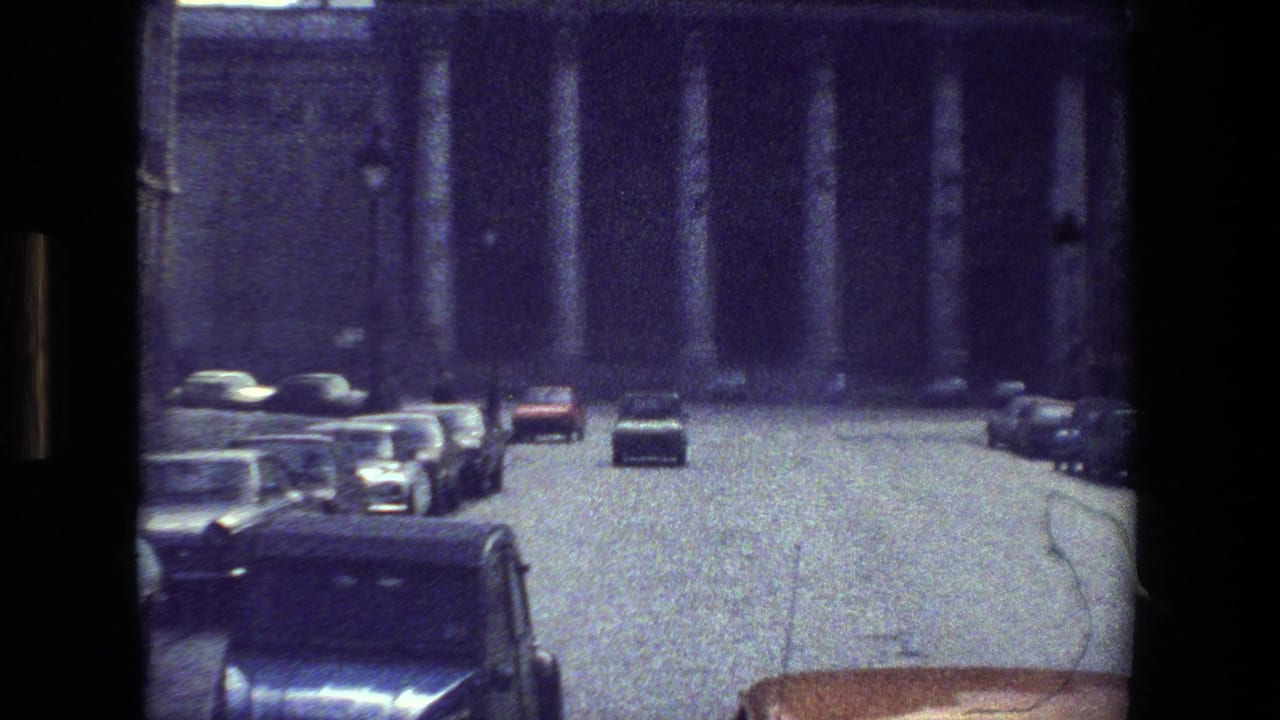 Cars on a street facing a building with large columns.