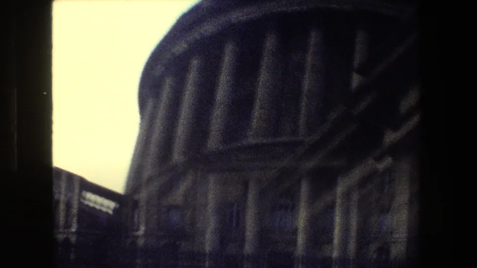 The final frame shows an angled close view of the domed structure and neighboring building edge, framed tightly in handheld 1981 Paris 8mm footage.