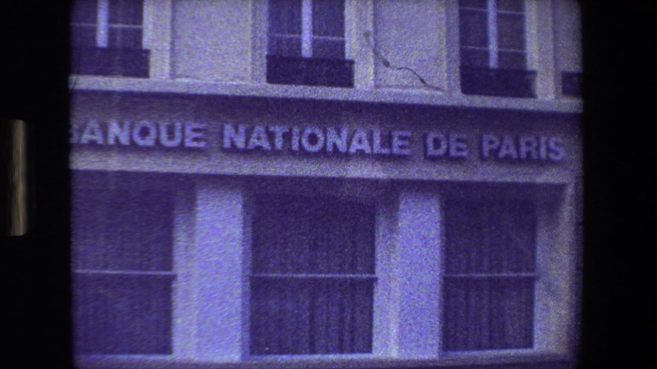 1981 Paris 8mm frame showing the Banque Nationale de Paris sign across a building facade, with windows above and a dark street reflection below.