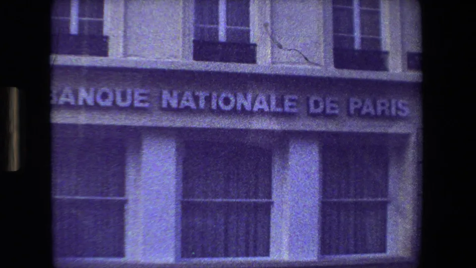 1981 Paris 8mm frame showing the Banque Nationale de Paris sign across a building facade, with windows above and a dark street reflection below.