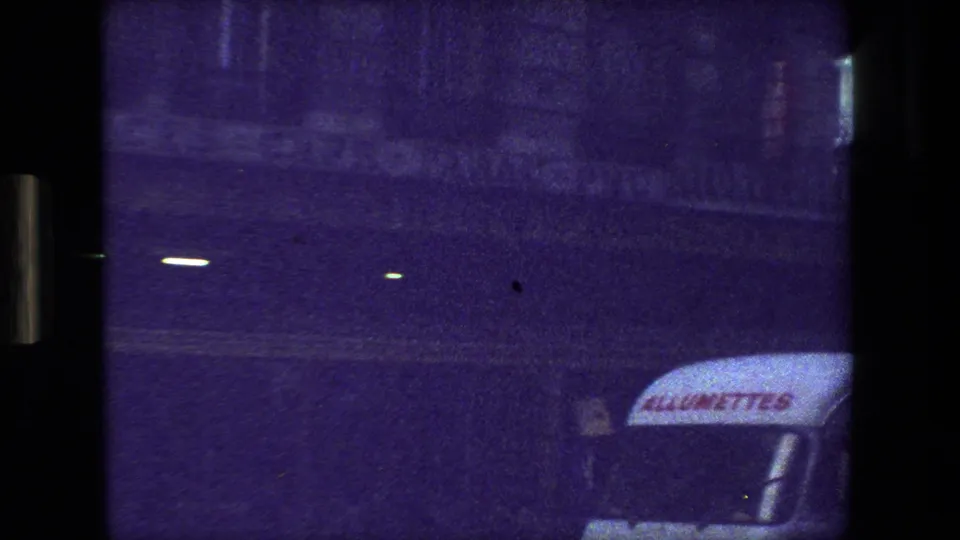 1981 Paris street frame showing a dim facade, the partial AlloMett awning text, and the front corner of a vehicle in grainy low light.