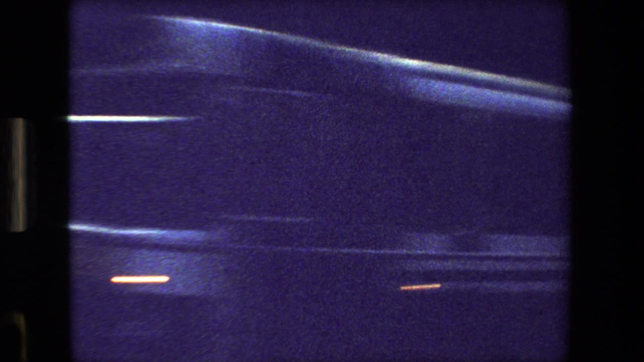 Purple-blue 8mm frame from Paris, France in 1981 showing a close, blurred view of a passing bus or large vehicle seen through glass.
