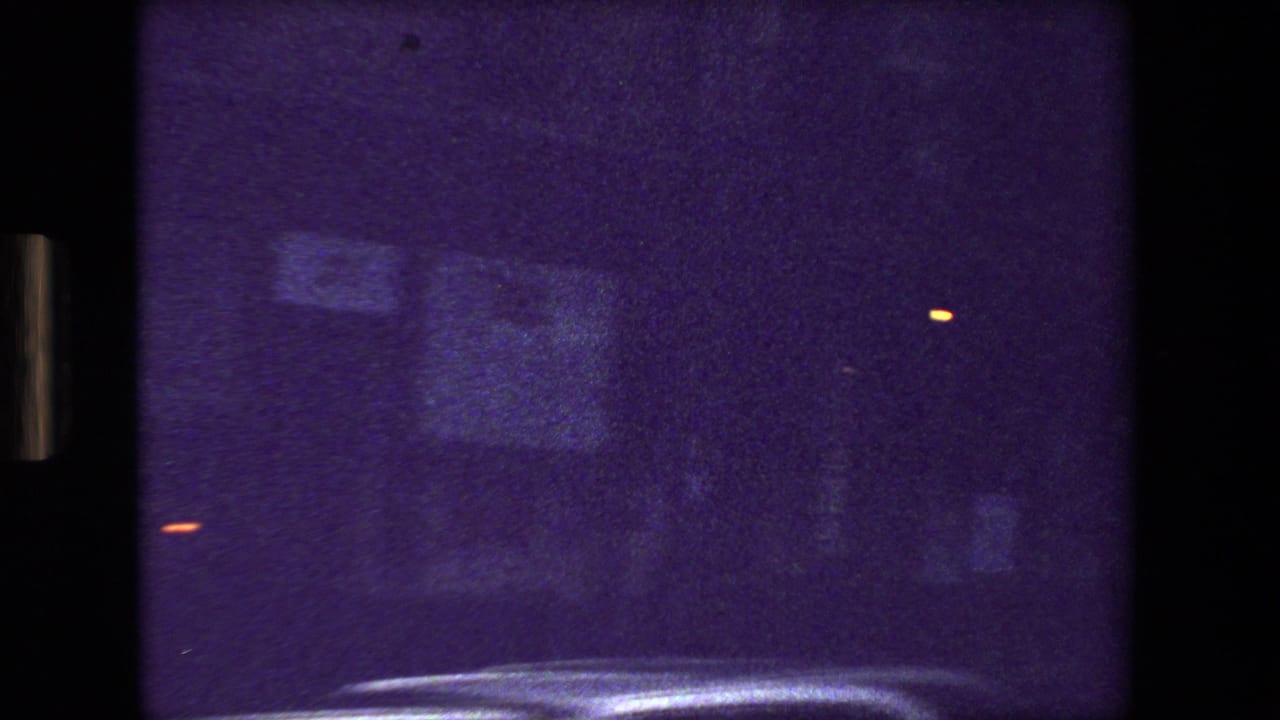 Dark purple street view with blurred reflections and small orange lights.