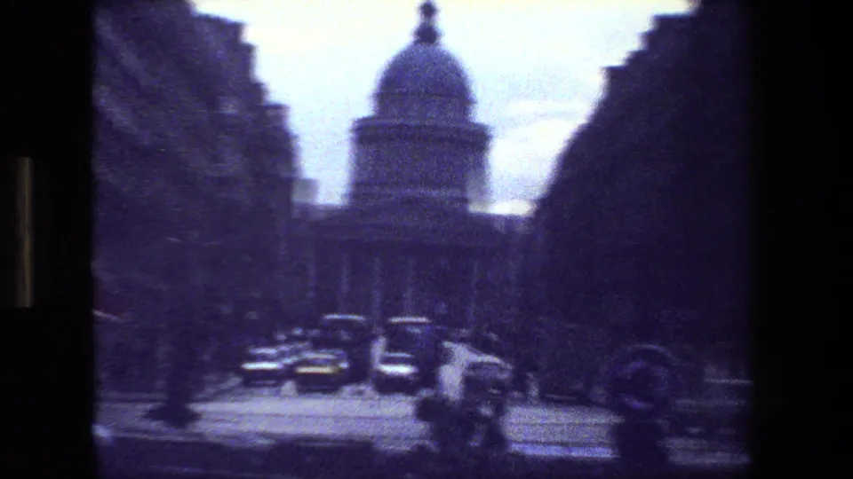 Paris street scene from 1981 showing a domed building at the end of a roadway, with cars, trees, and shadowed building edges framing the view.