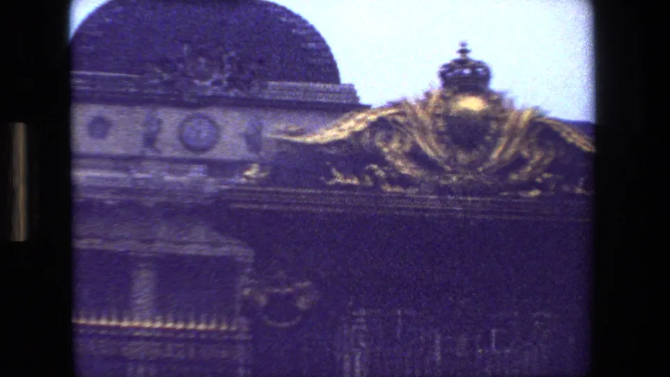 1981 Paris 8mm frame showing a domed roofline, pale sky, and gilded architectural ornament above dark iron gatework.