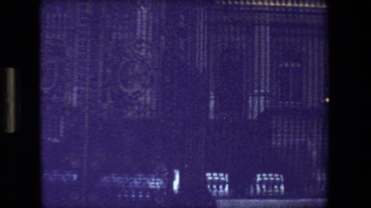 Purple-tinted view of faint building details through a dark film frame.