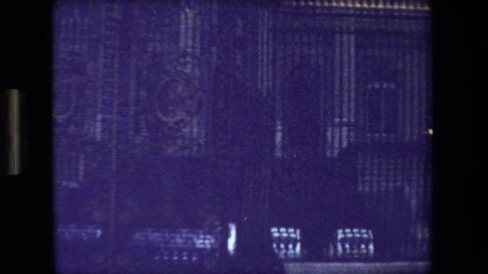 Purple-tinted 1981 home-movie frame from Paris showing indistinct architectural lines and window reflections seen through a dark 8mm film border.