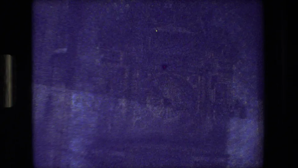 Very dark purple-tinted 8mm frame from the moving Paris view, with only faint urban shapes and film texture visible.