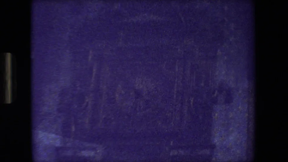 Purple-tinted closing frame of the 1981 Paris car-window view, showing indistinct railing-like lines, soft reflections, and heavy 8mm grain.