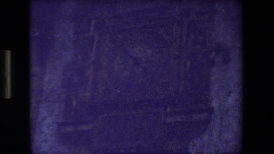 Dark opening frame from the supplied 1981 Paris 8mm clip, with heavy blue cast, soft indistinct shapes, and visible film gate borders.