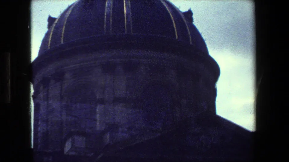 1981 Paris 8mm frame showing a close, underexposed view of a domed building detail with curved rooflines against a bright overcast sky.