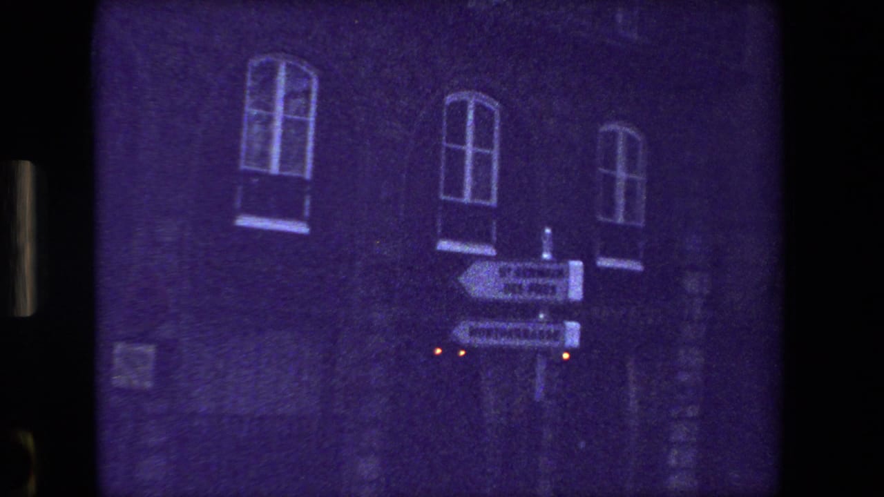 Brick building facade with illuminated arched windows and small points of street light.