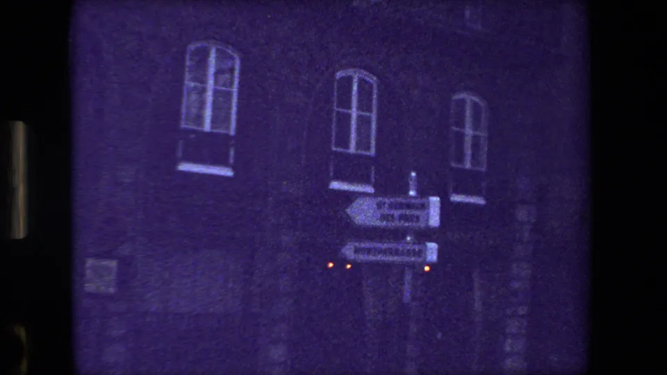 Purple-tinted Paris 8mm frame showing an urban brick or stone facade with arched windows, one lower window area, and small glowing streetlights.