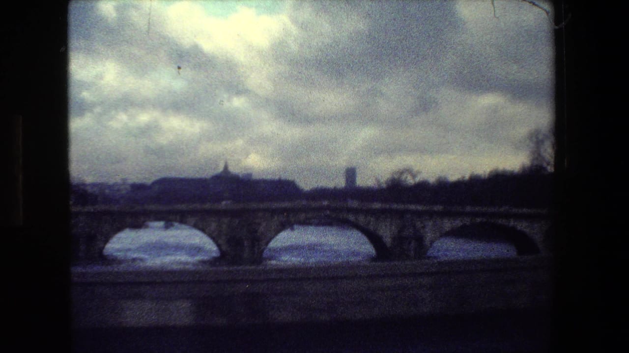 Paris, France 1981 frame with multiple stone bridge arches, a river below, and distant skyline forms silhouetted beneath a dramatic overcast sky.