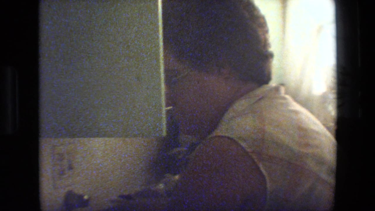 Adult woman with glasses turned downward beside a bright interior light source.