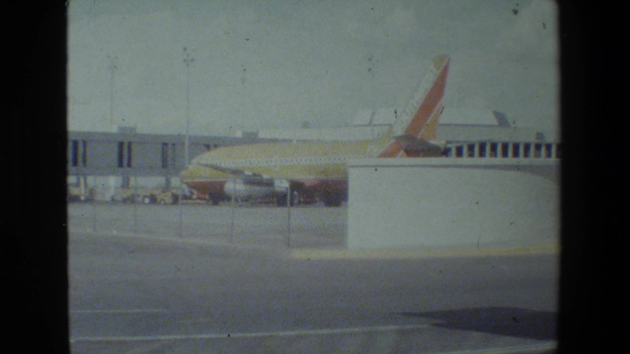 Southwest jet at the gate behind a white structure and terminal walkway.