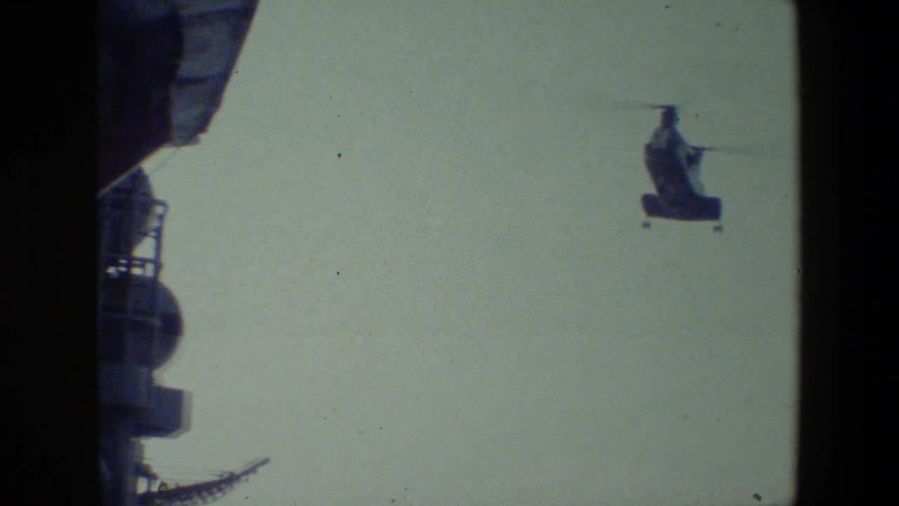 A distant tandem-rotor military helicopter appears in flight near the dark superstructure of a ship in metadata-supported 1981 8mm footage.