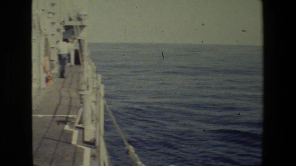 Later frame from the 1981 8mm clip showing the vessel side deck, railings, and open blue sea stretching to a soft horizon.