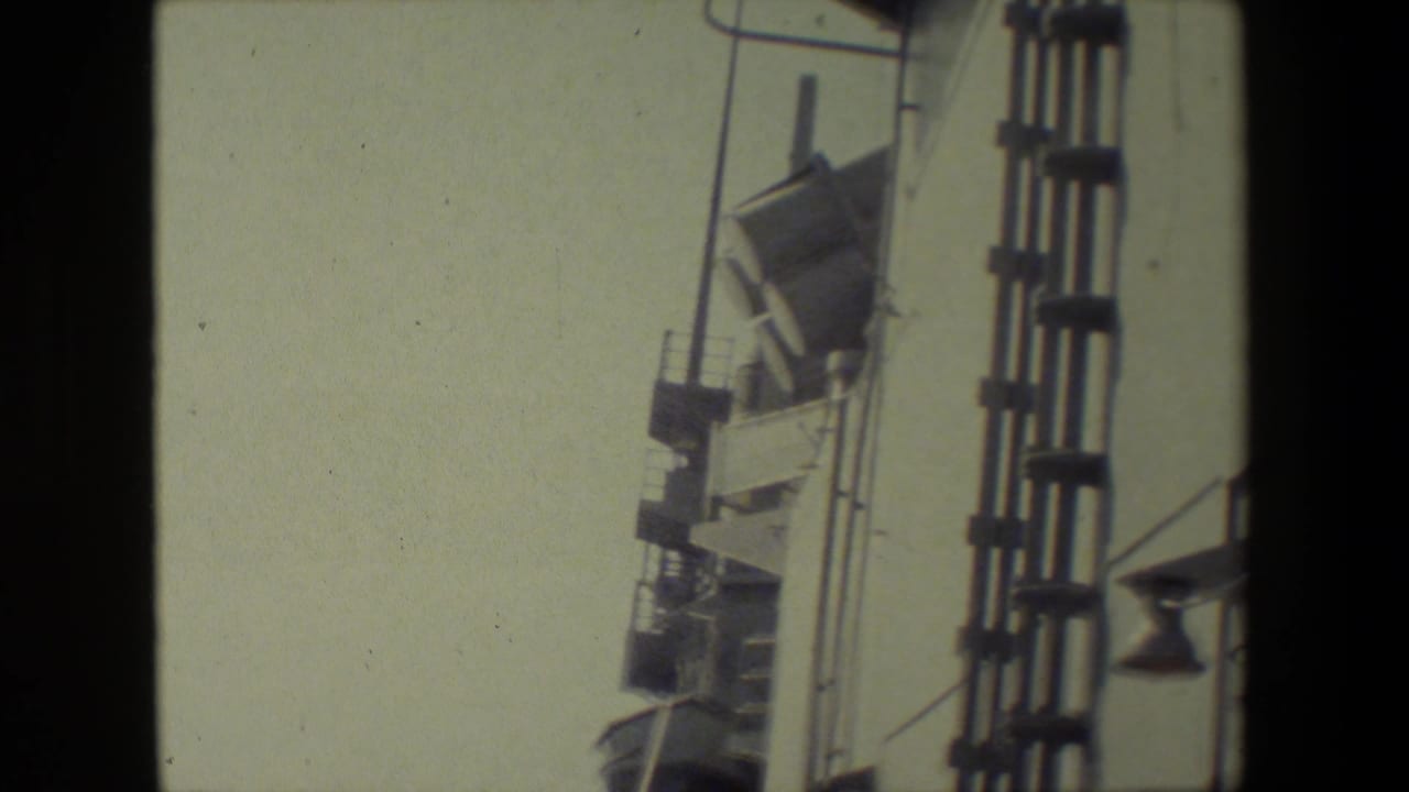 Ship structure and railings against a pale sky with part of the sea below.