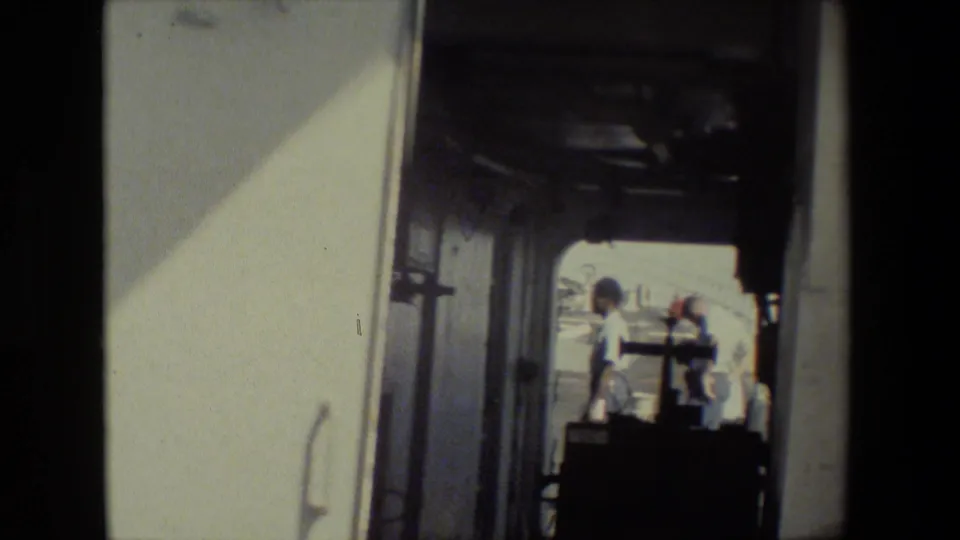 A darker, closer view through the open doorway shows two people outside, one near a dark object that appears to be equipment or a cart, with the trailer interior filling much of the frame.