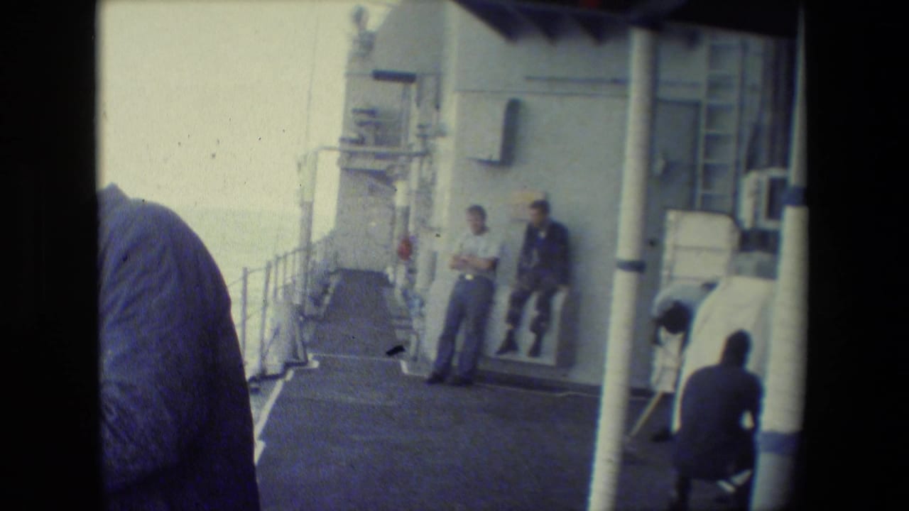 Several sailors on a ship deck with railings and deck equipment visible.